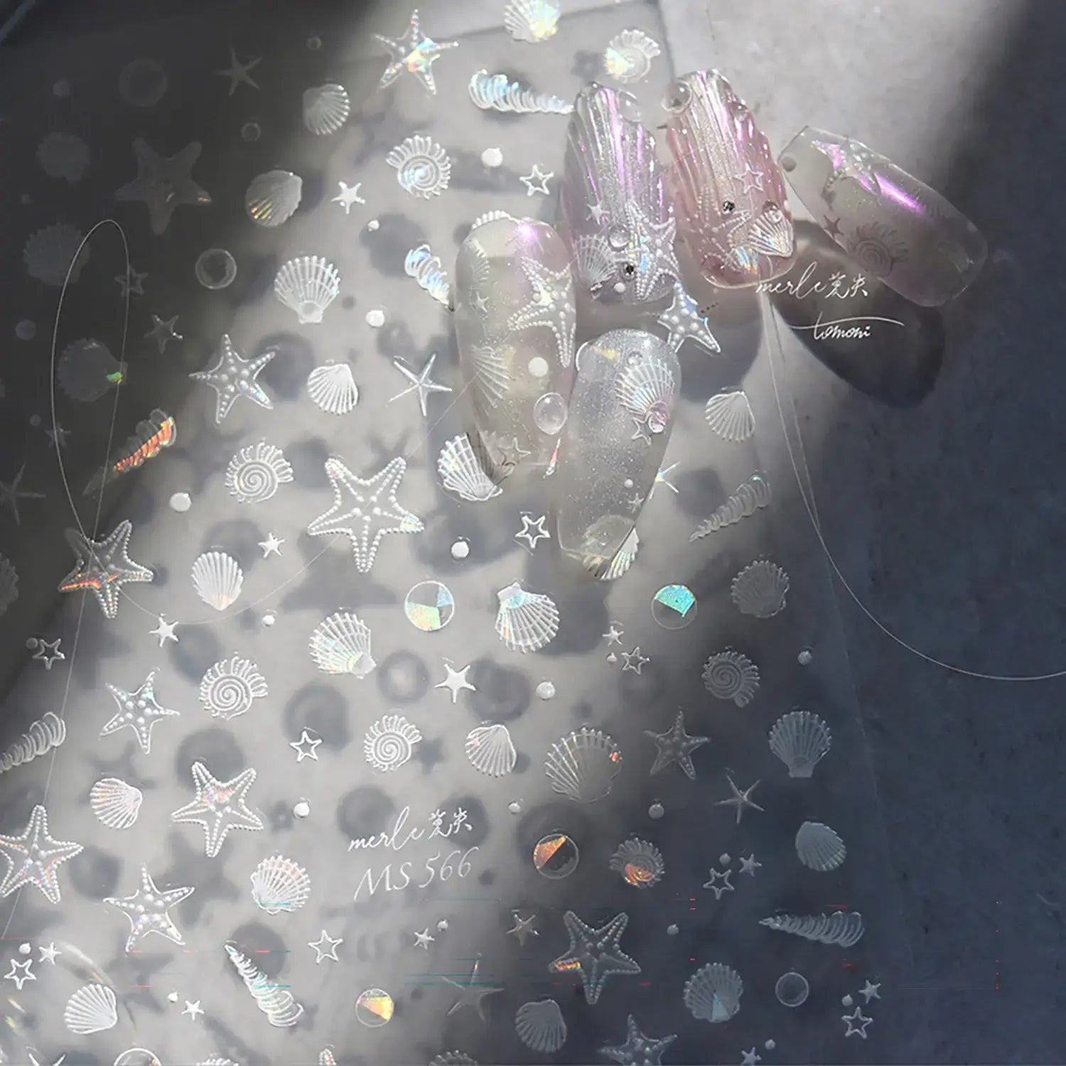 Translucent nail art sheet with starfish, shell, and mermaid-themed designs on a gray background.