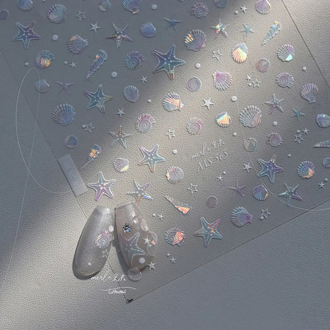 Nail art stickers with starfish and shell designs on a gray surface.