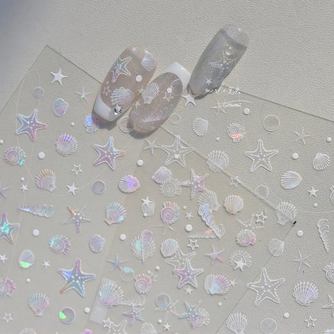 Nail art stickers with starfish, seashells, and moons on a light gray background